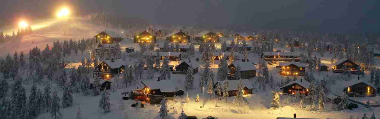 Vy över stugorna i Toppbyn i Orsa Grönklitt i vackert vinterlandskap på kvällen.