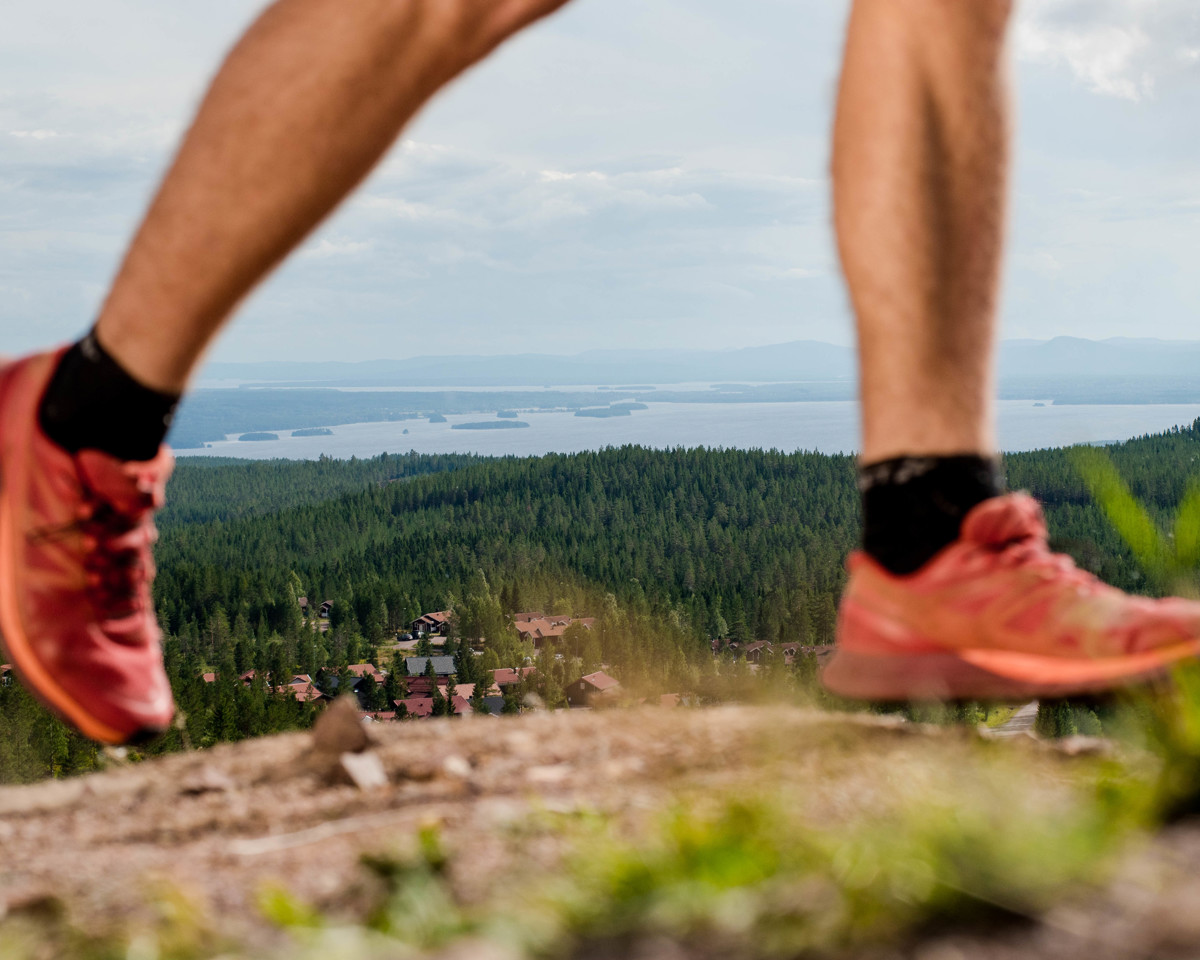 Close-up of a runner with a view of forests and a lake in the background.
