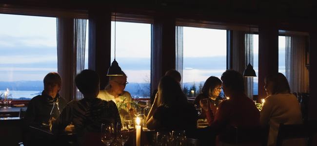 Guests dining by candlelight with a view of Lake Orsa at dusk.
