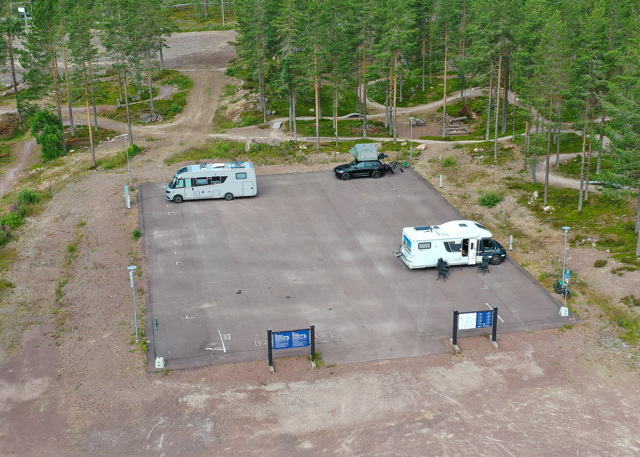 Motorhome parking area surrounded by forest and cycling trails.