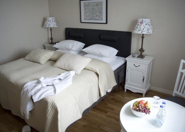 Cozy bedroom with double bed, light textiles, and fruit bowl on a small table.