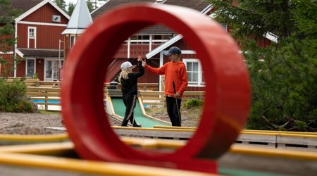 Två barn gör high five vid en minigolfbana.