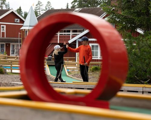 Two children high-five at a mini golf course.