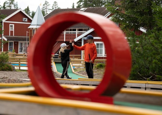 Två barn gör high five vid en minigolfbana.
