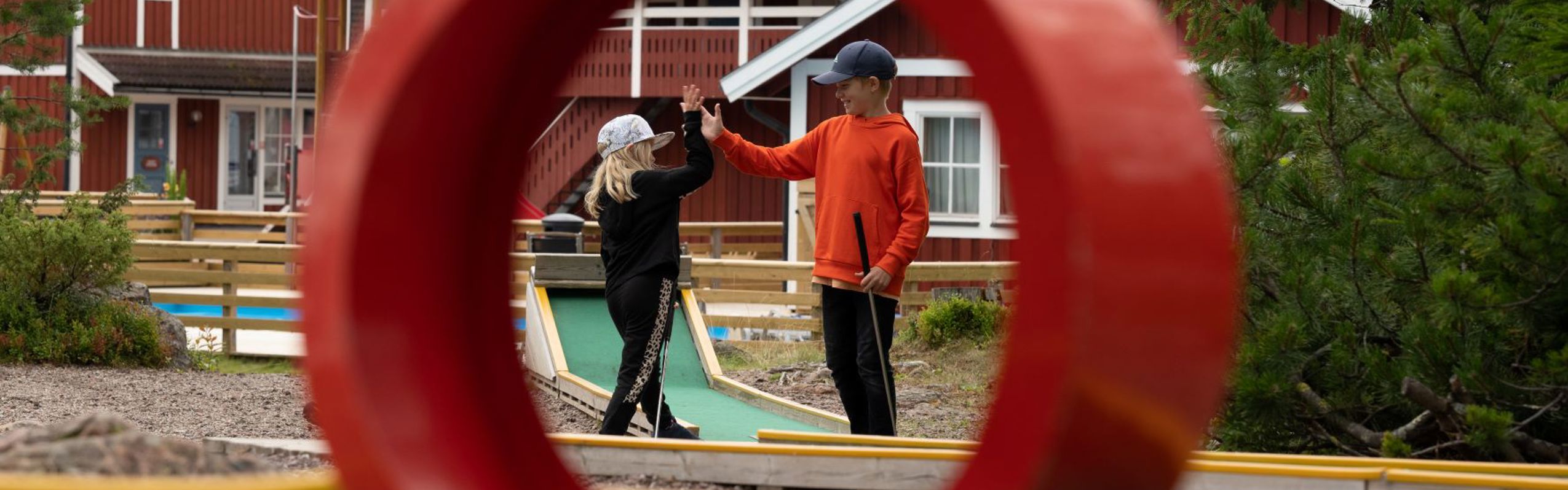 Two children high-five at a mini golf course.