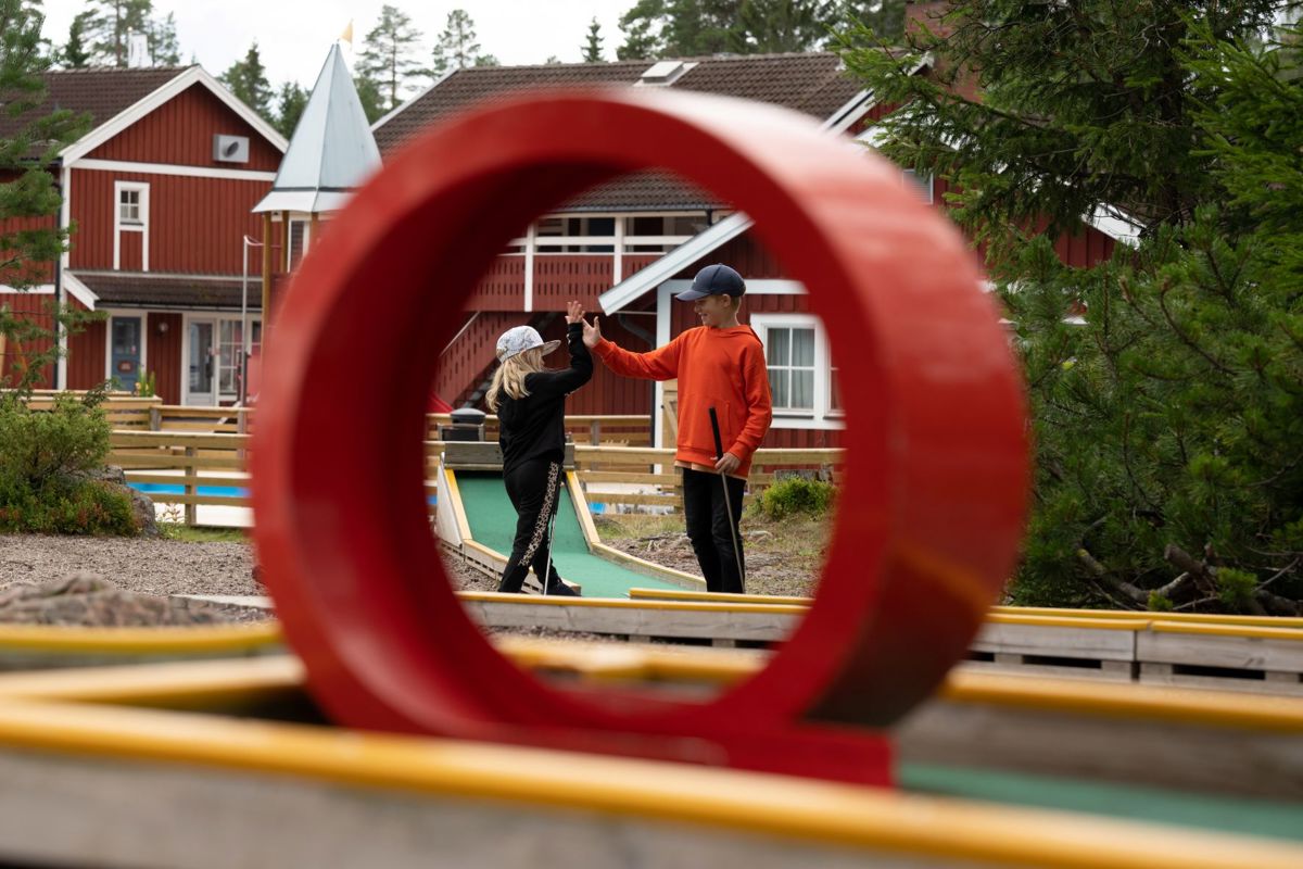 Two children high-five at a mini golf course.