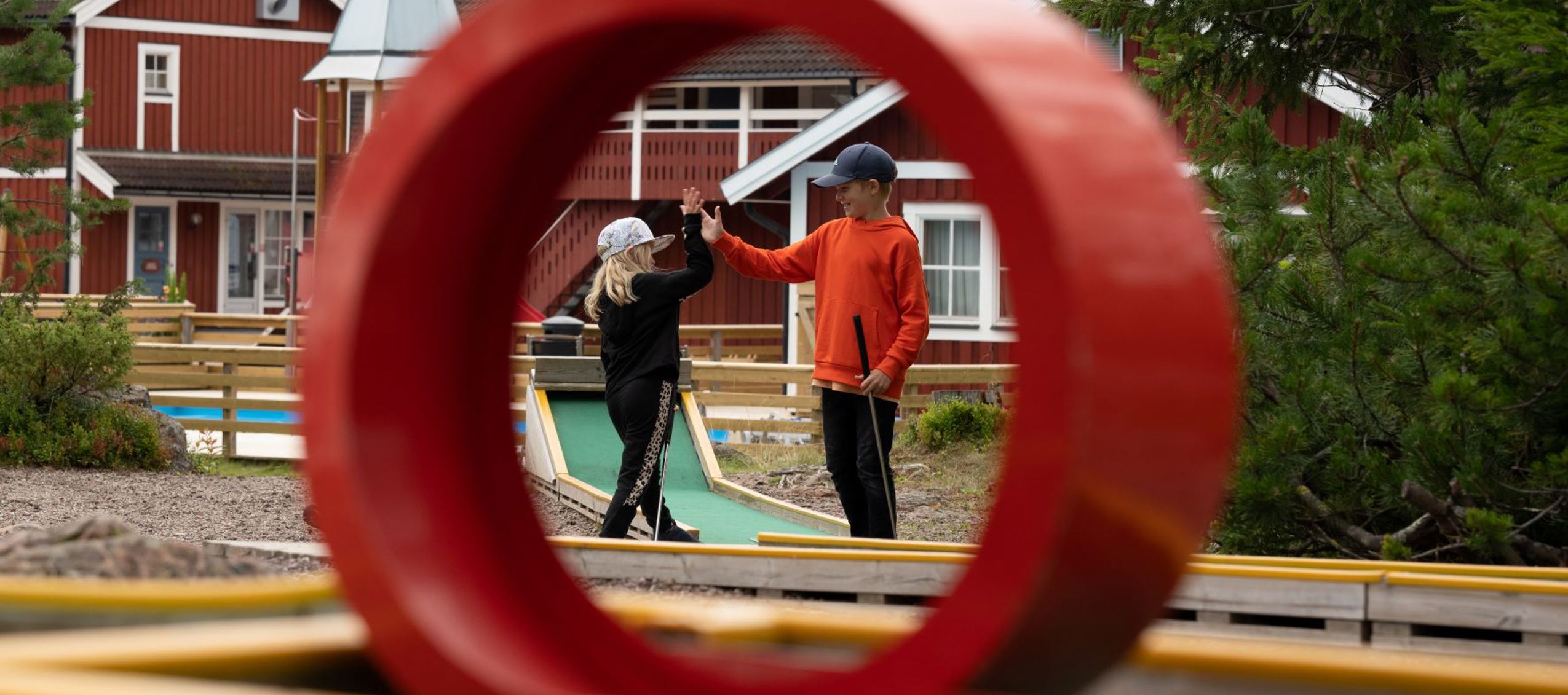 Två barn gör high five vid en minigolfbana.