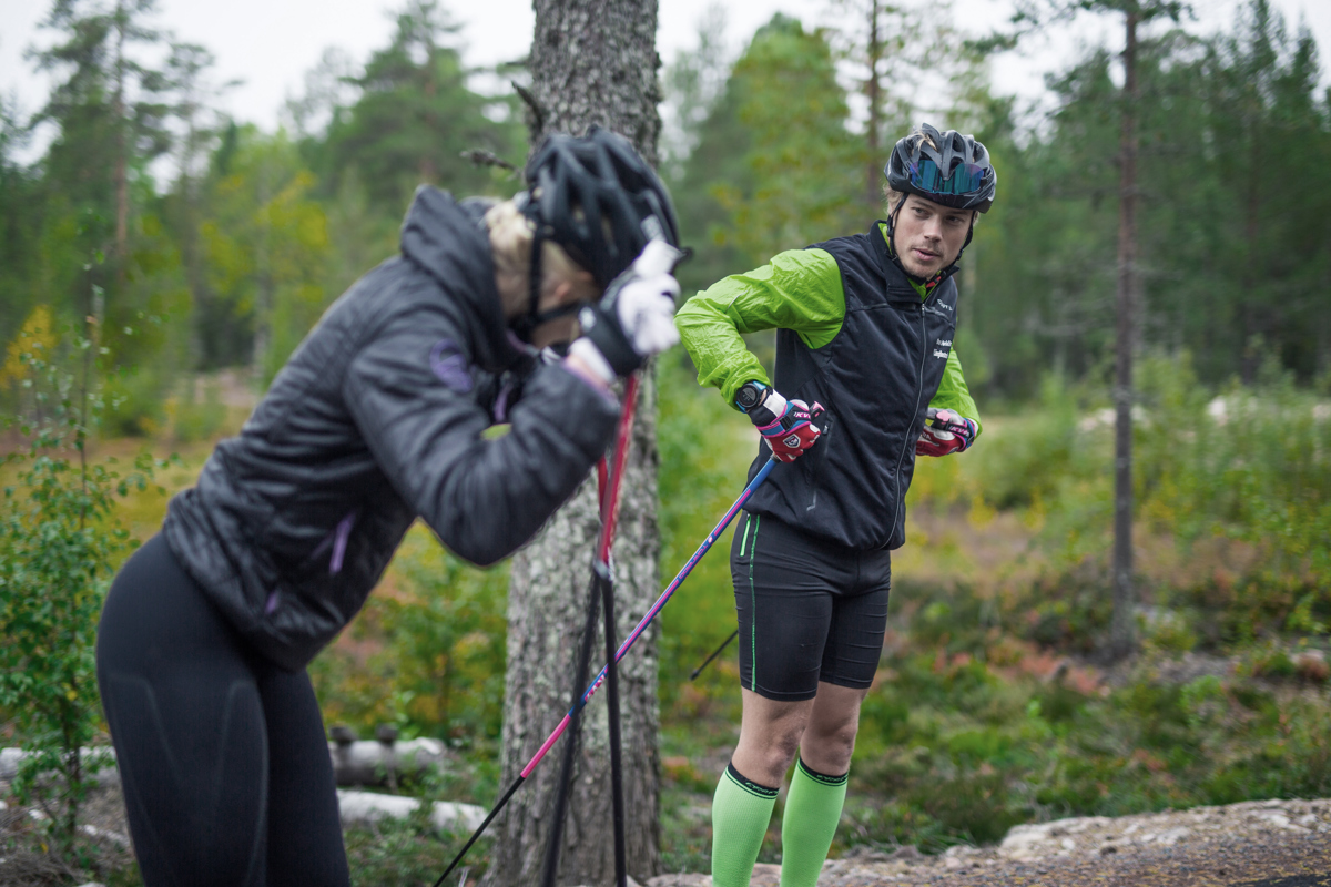 Två personer med rullskidor där en visar teknik i skog