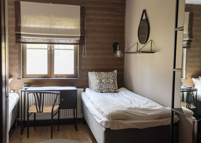 Small bedroom with single bed, desk, and window with dark frames.