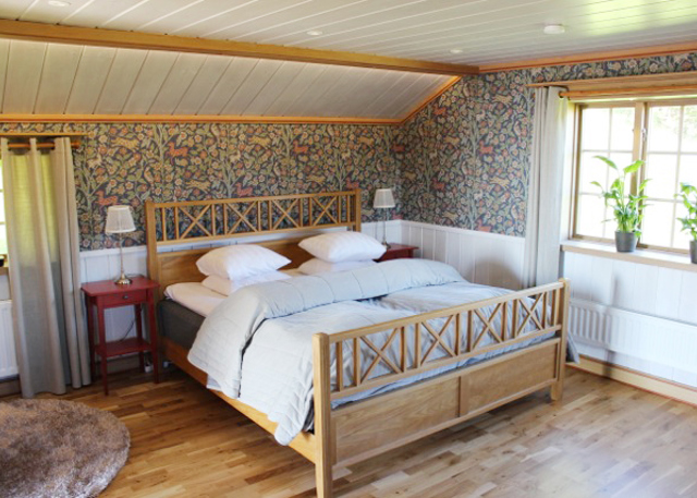 Bedroom with wooden frame bed, floral wallpaper, and warm lighting in traditional style.