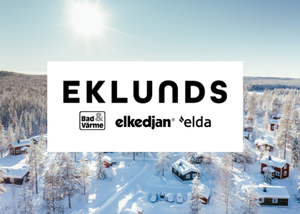 Logotyp för Eklunds centrerad över en solig vinterbild med snötäckta stugor och skog i bakgrunden.