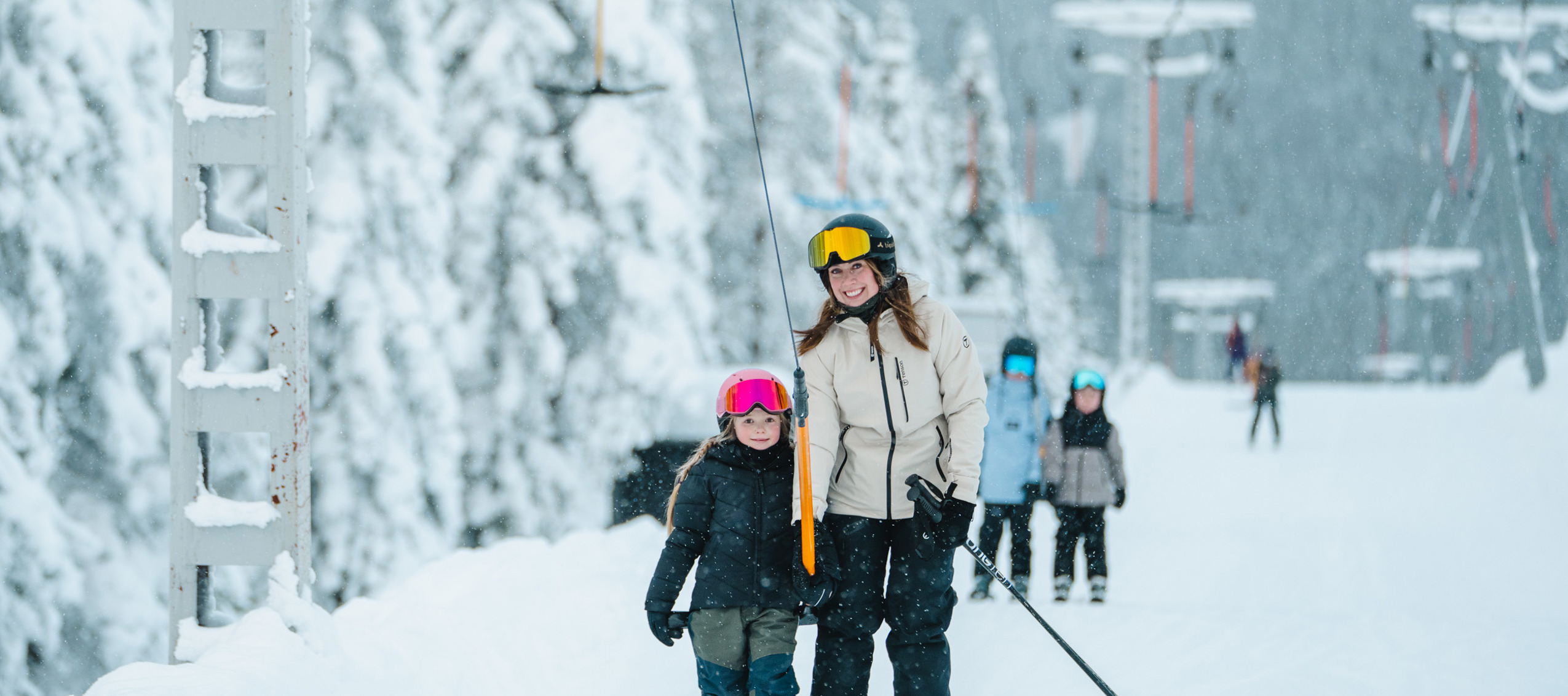 Vuxen och barn med skidor vid lift i snötäckt backe