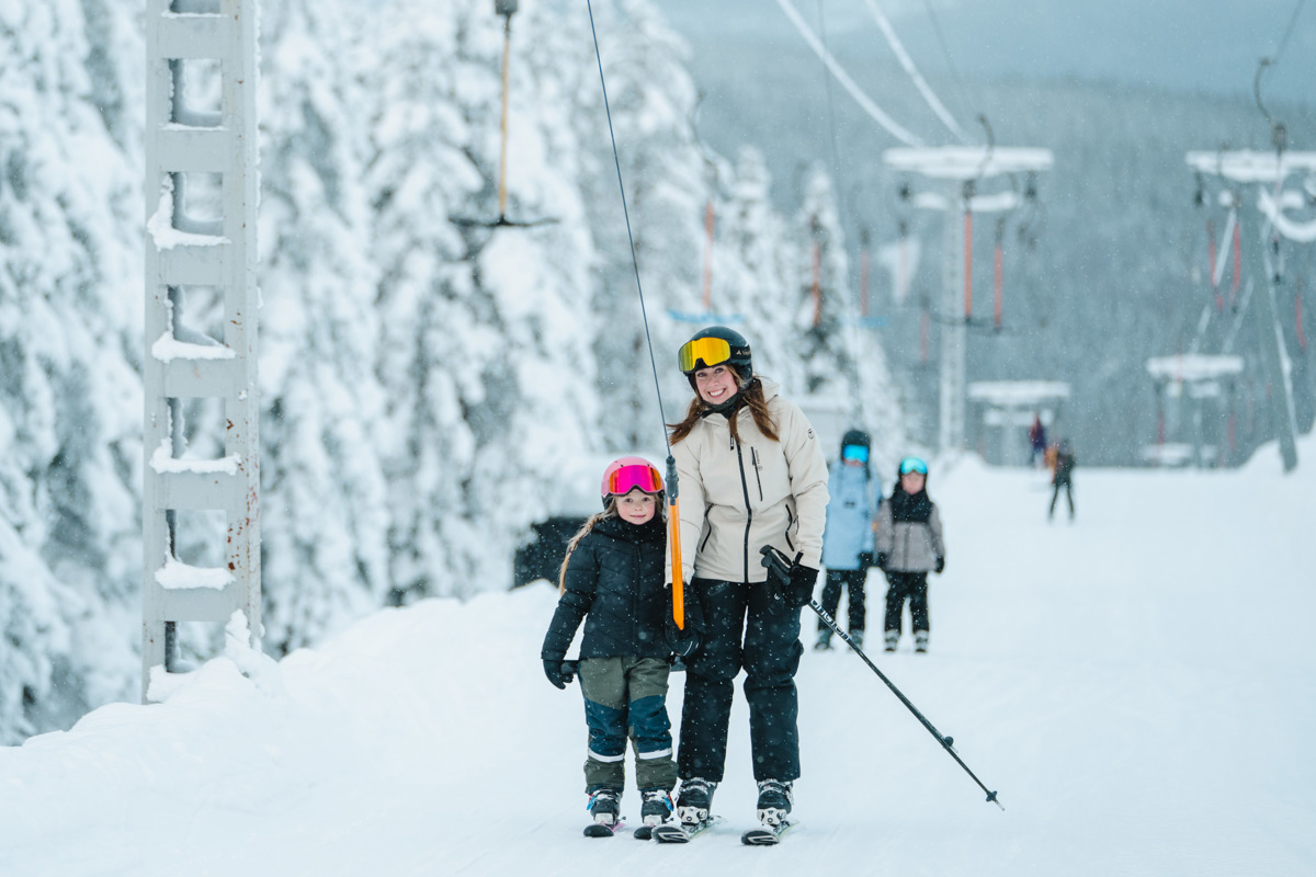Adult and child with skis near lift on snowy slope