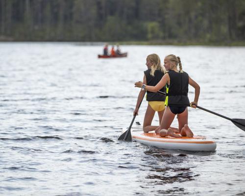 Två barn paddlar SUP på Rädsjön med flytvästar