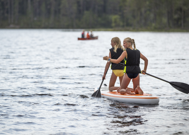 Två barn paddlar SUP på Rädsjön med flytvästar