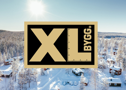 Logotyp för XL bygg centrerad över en solig vinterbild med snötäckta stugor och skog i bakgrunden.