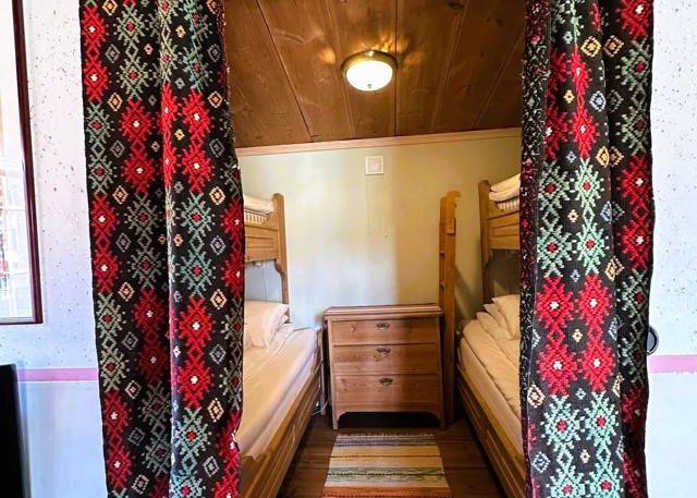 Bedroom with two bunk beds, wooden floor, and colorful patterned curtains.