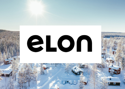 Logotyp för Elon centrerad över en solig vinterbild med snötäckta stugor och skog i bakgrunden.
