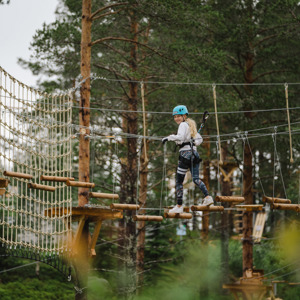 Tjej som klättrar över ett hinder i Grönklitts klätterpark