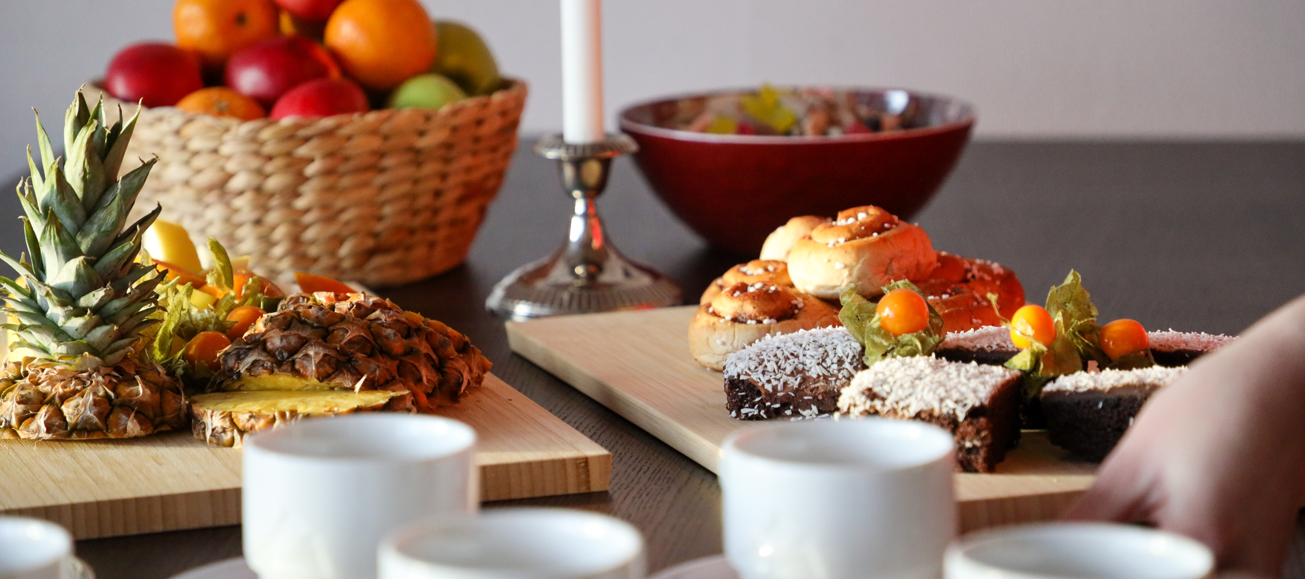 Uppdukat fika med fruktfat, bakverk och kaffe­koppar i varm och inbjudande miljö.