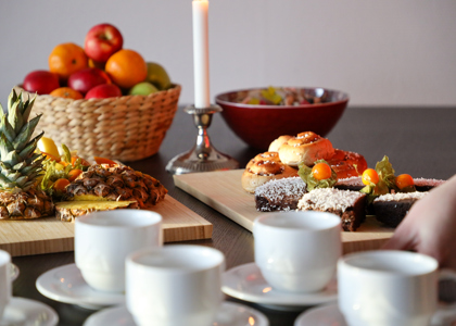 Uppdukat fika med fruktfat, bakverk och kaffe­koppar i varm och inbjudande miljö.