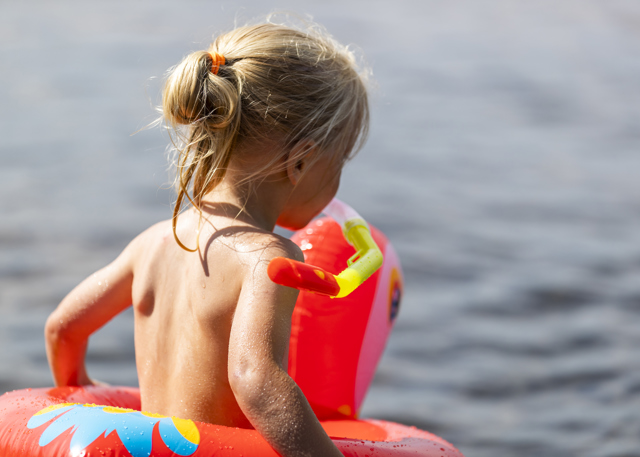Lille barn med badering på vej ned i vandet.