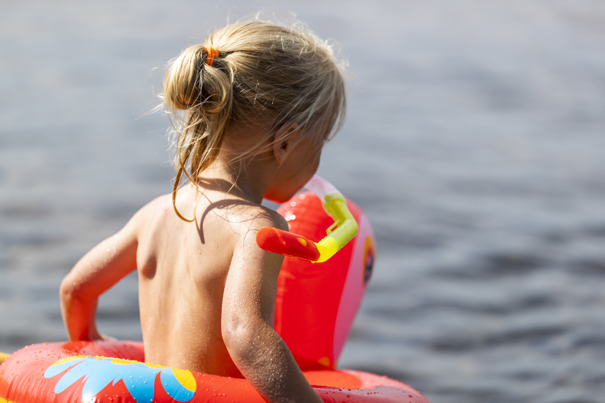 Lille barn med badering på vej ned i vandet.