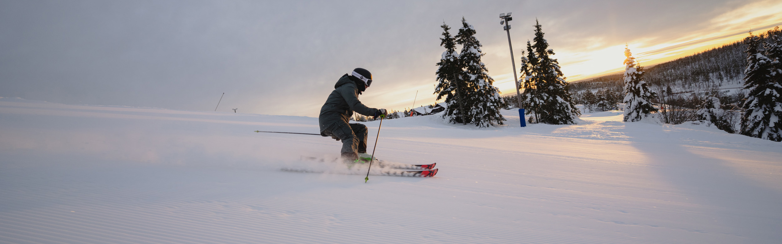 Alpin skidåkare svänger nedför en preparerad skidbacke i ett snötäckt vinterlandskap.