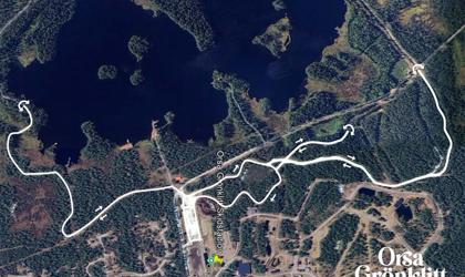 Flygbild över Orsa Grönklitt med en vit markerad skid- eller löpslinga ritad ovanpå kartan, som visar sträckningen genom skog och runt sjöar nära skidstadion.