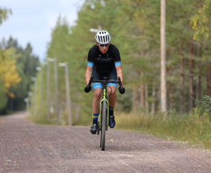 Person cyklar gravel på grusväg i skogsmiljö