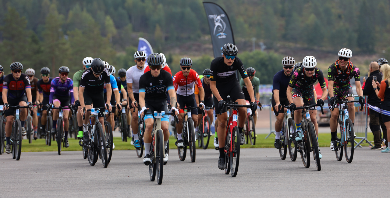 Stort startfält med cyklister i färgglada kläder vid starten av en cykeltävling i Orsa Grönklitt.