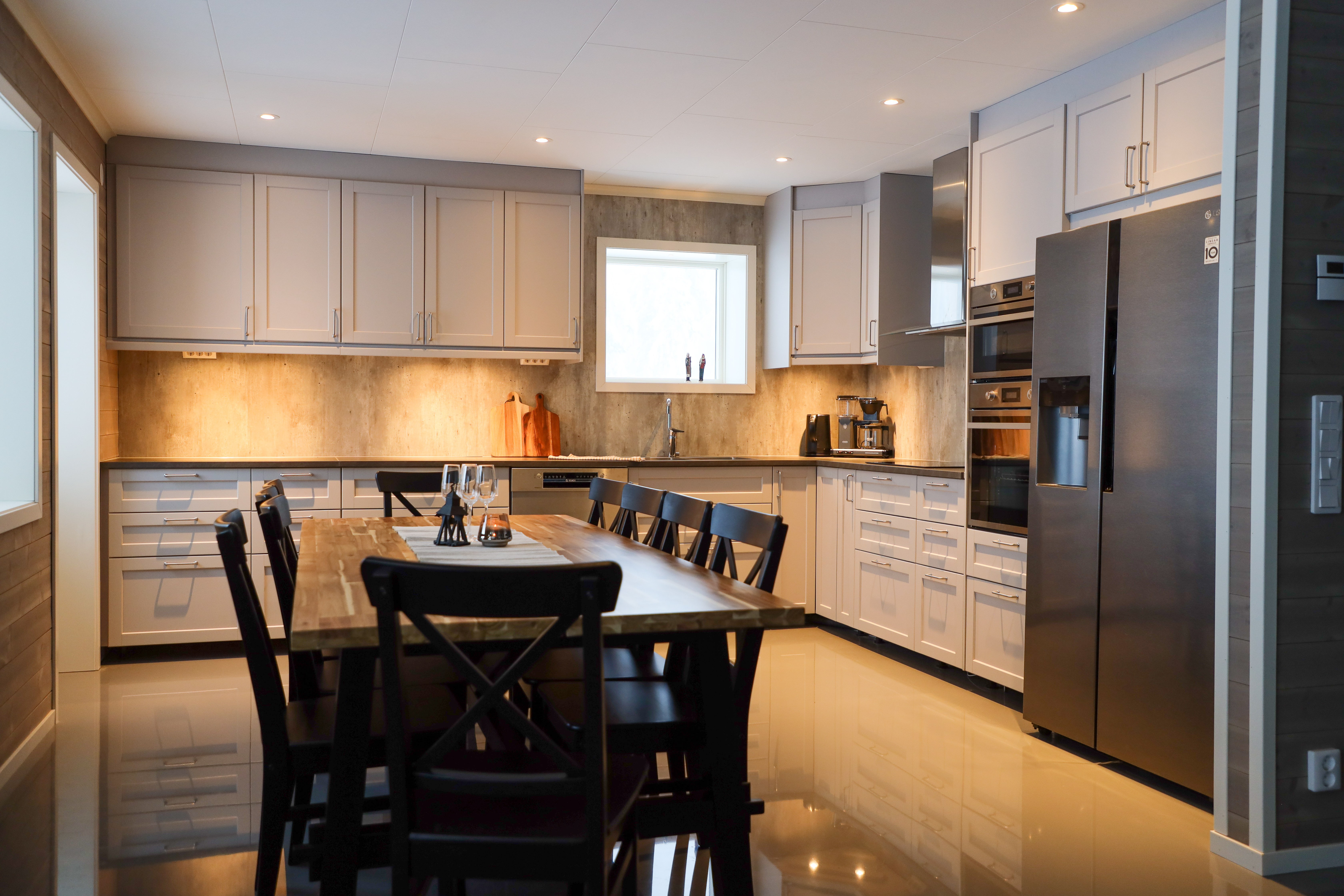 Large modern kitchen with grey cabinets, stainless steel appliances, and dining table with chairs.