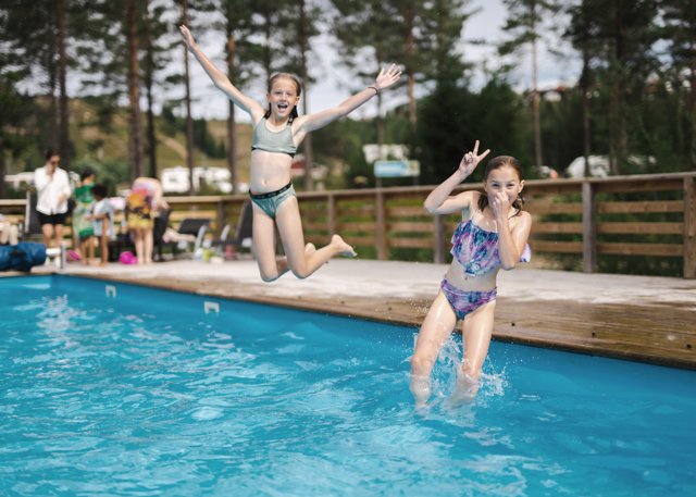 Två barn hoppar ner i en utomhuspool