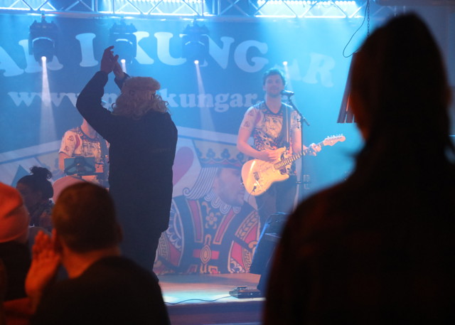 En sanger spiller guitar på scenen foran publikum til en aften med livemusik.