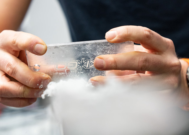 Close-up of hands scraping wax off a pair of cross-country skis.