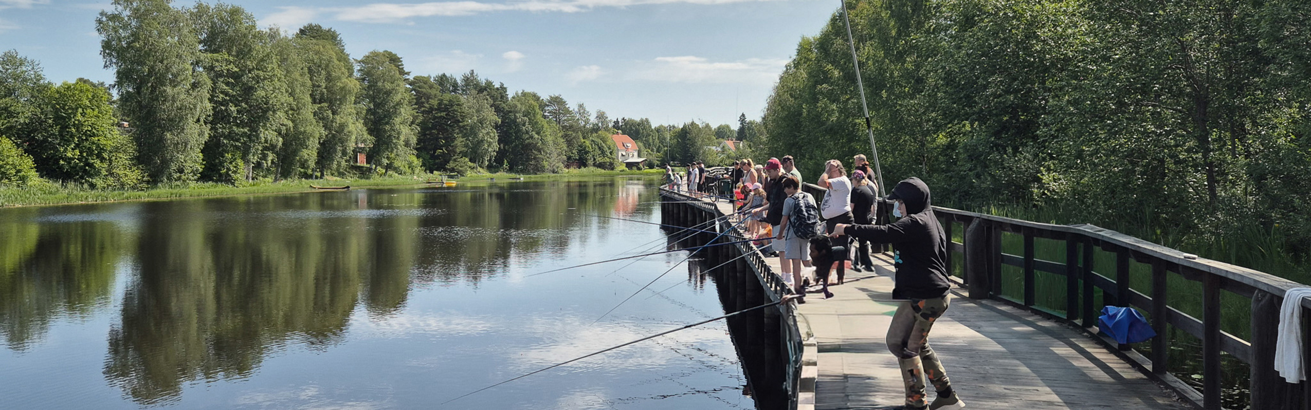 People fishing from accessible pier along calm river in Orsa
