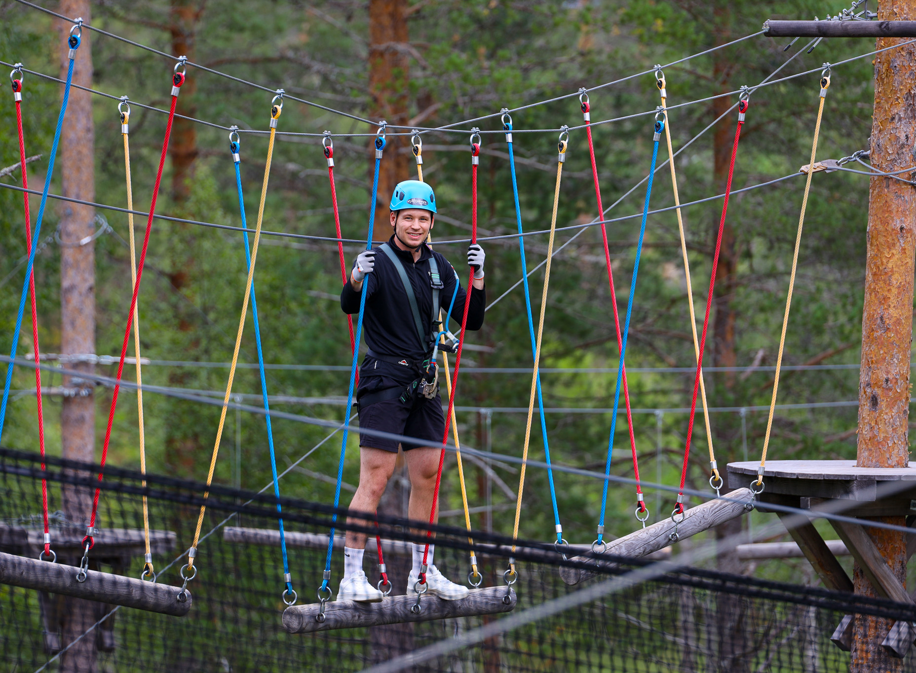 Person med hjälm går balanshinder i höghöjdsbana i skog