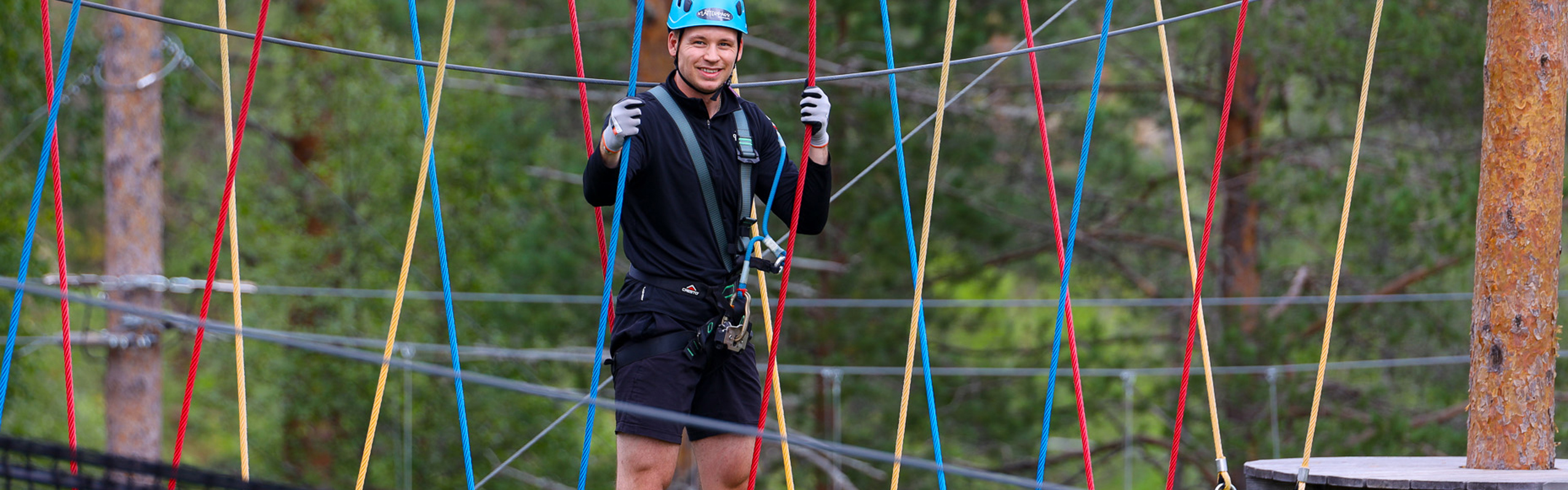 Person wearing helmet crossing balance obstacle in high ropes course