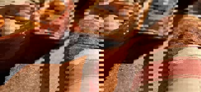 Close-up of freshly baked bread and small rolls on a wooden tray with a linen napkin.