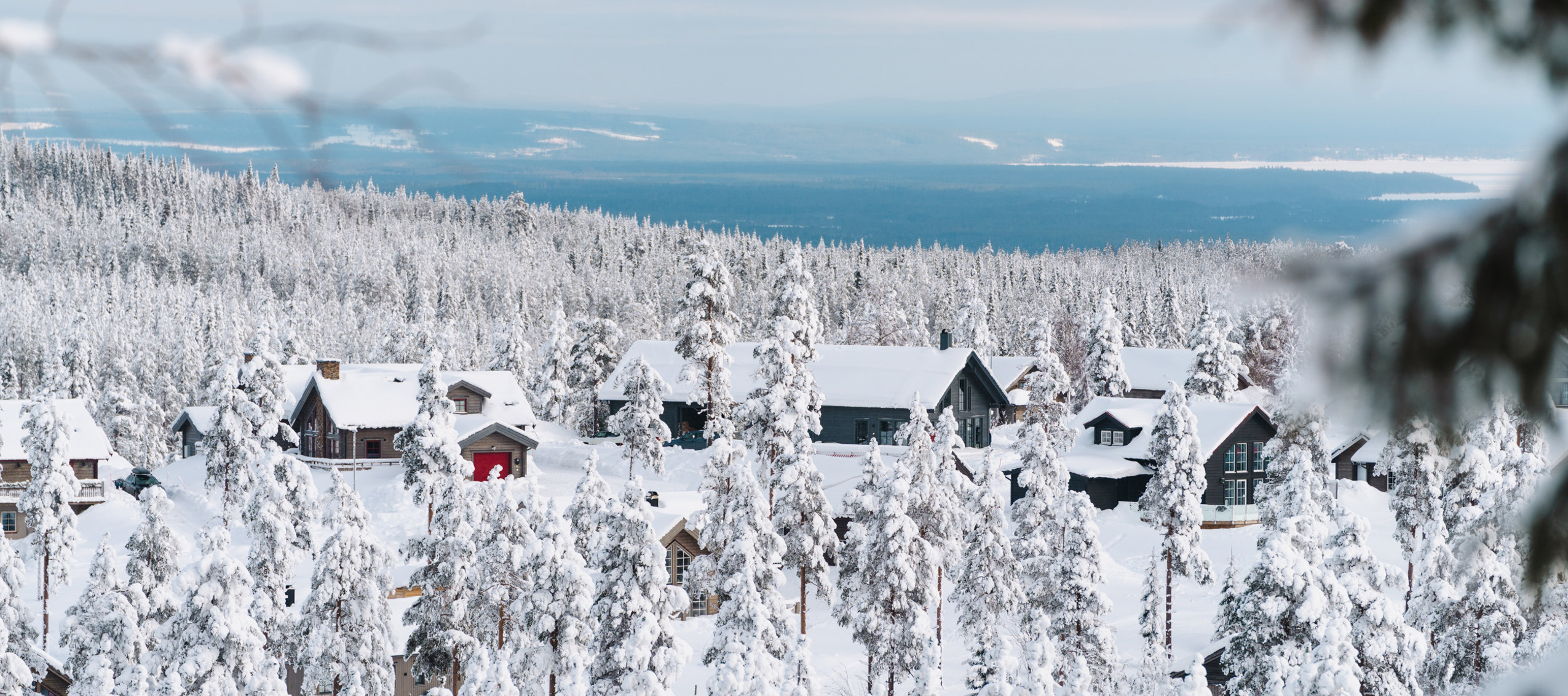 Snötäckta stugor bland frostiga tallar i vinterlandskap